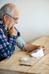 Hombre mayor controlando la tensión y anotando resultados