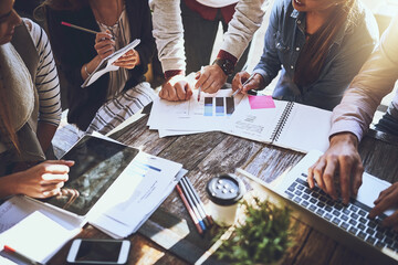Success is all a numbers game. Cropped shot of a group of colleagues having discussing paperwork during a meeting at a cafe.