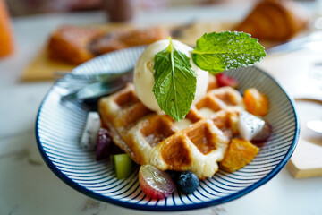 Organic mint on top of blur waffles with ice cream background serve on a table background in cafe restaurant.
