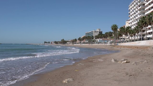 Villajoyosa beach and town Spain with palm trees sand waves and buildings Costa Blanca Alicante