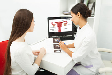 Gynecology, consultation of gynecologist, women's health. Gynecologist showing to woman ultrasound of her ovaries during female patient visit to gynecology - obrazy, fototapety, plakaty