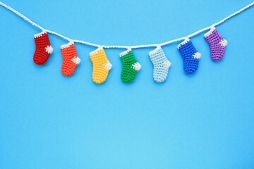 Christmas stockings hanging on blue background. Colorful rainbow socks. Odd socks day mismatched concept. Social school bullying. Top view flatlay idea for postcard with copy space for text. Close up