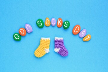 Odd socks day lettering and mismatched colourful socks on blue background. Social school bullying concept. Lost lonely socks. Top view flatlay idea for poster, banner, advertising