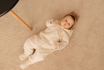 Seven month girl is lying on the carpet in the overalls