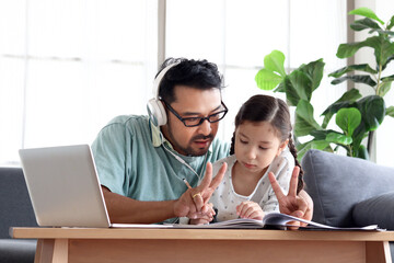 Young handsome father teach adorable girl daughter to do school homework, using laptop computer for e-learning study at home, dad and kid spend time together for education and searching Internet.