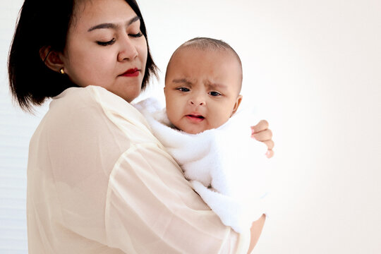 A Six Month African American Infant Baby Covered With White Towel After Taking A Bath In Bathroom, Mother Holding Little Kid After Washing And Cleaning Her Child In Bath Already.