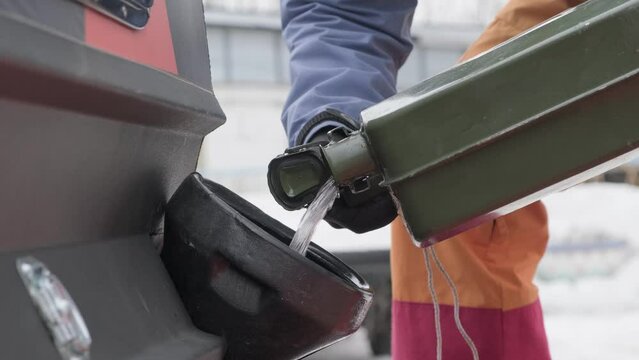 Close-up of a man's hands pouring gasoline from a canister into a tank