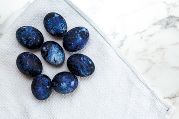 Cosmic colored eggs lie on a white waffle towel on a marble table. Easter eggs on the table