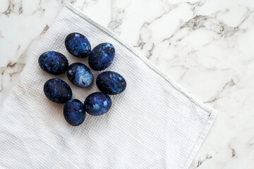 Cosmic colored eggs lie on a white waffle towel on a marble table. Easter eggs on the table