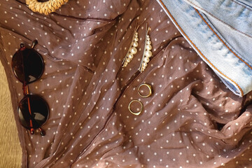 Brown polka dot blouse, vintage mom jeans, straw bag, round sunglasses, gold rings and pearl hair...