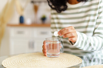 Faceless ethnic female washing down pill with glass of water. Healthy supplement remedy treatment