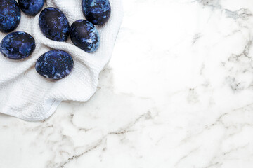 Cosmic colored eggs lie on a white waffle towel on a marble table. Easter eggs on the table