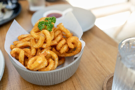 Golden Spicy Seasoned Curly Fries on rustic plate. fast food snack with ketchup on restaurant background. Unhealthy junk food. ready to eat