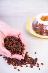 Close-up of raisins in the palms of the hands, on a wooden background, baking a cupcake. vertical frame