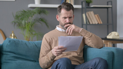 Man Reacting to Loss on Documents, Sofa 