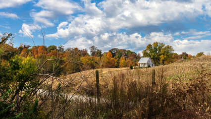 Rural autumn southern Illinois countryside landscape with aging farmhouse on a hillside under a...
