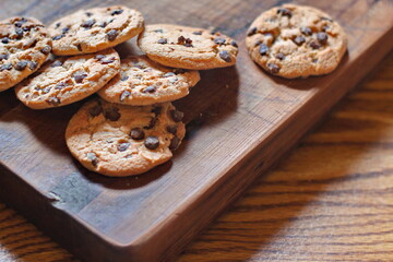 Freshly baked chocolate cookies served on a wooden cutting board.