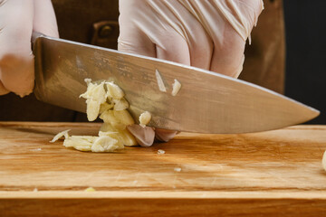 Cooking food. Sliced garlic with a knife. Shallow depth of field