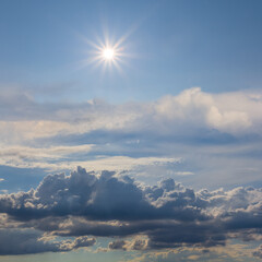 Naklejka na ściany i meble sparkle sun among dense cumulus clouds, natural cloudy sky background