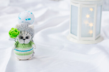 a knitted kitten with knitting needles, colored balls of thread in a basket. Creative workshop on needlework handmade