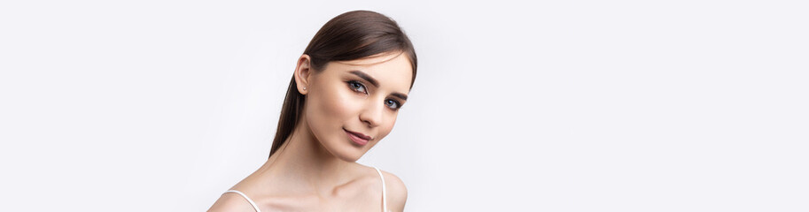 Fototapeta premium Beautiful smiling woman with clean skin, natural make-up and white teeth on a gray background