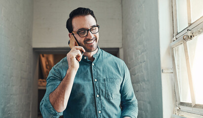 Yes, thats me.... Cropped shot of a handsome young male architect taking a phonecall while standing in an office.