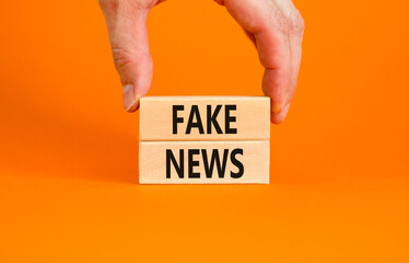 Fake news symbol. Wooden blocks with concept words Fake news on beautiful orange background. Businessman hand. Business media and fake news concept. Copy space.