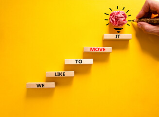 We like to move it symbol. Concept words We like to move it on wooden blocks. Businessman hand. Beautiful yellow table yellow background. Business motivational We like to move it concept. Copy space.