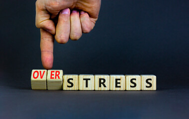 Over stress symbol. Psychologist turns wooden cubes and changes the concept word Stress to Over stress. Beautiful grey table grey background, copy space. Psychlogical over stress concept.