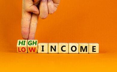 Low or high income symbol. Businessman turns wooden cubes and changes words Low income to High income. Beautiful orange table orange background, copy space. Business low or high income concept.
