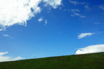 Obraz na płótnie Canvas Blue sky over green grass rising up. Movement up the ground.Summer landscape with clouds.