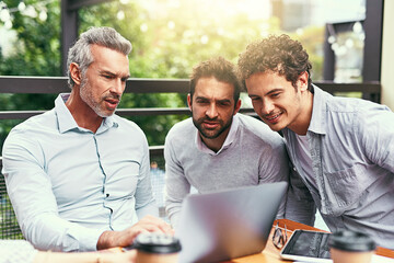 Three of the best in business. Shot of a team of colleagues using a laptop together during a meeting outdoors.