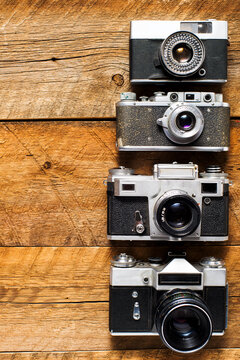 Old retro cameras on vintage wooden boards abstract background.