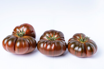 Black raf tomato,three tomatoes with different shapes on white background.