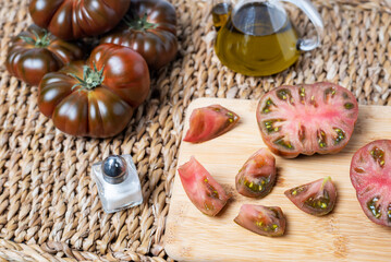 Tomato of the Raf variety open and chopped on a cutting board, together with oil and salt.