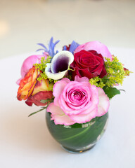 Small rounded vase of roses and other flowers on a white background