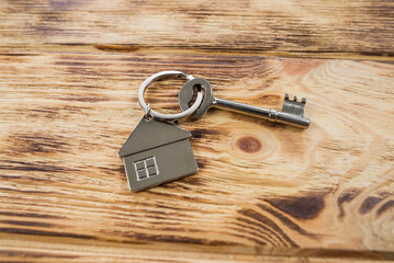 metal keychain in the form of a house on a wooden background.