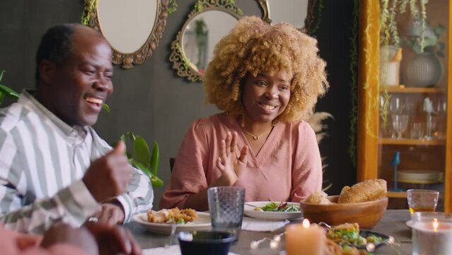 Positive African American Woman Telling Story To Family Members At Home Dinner Party