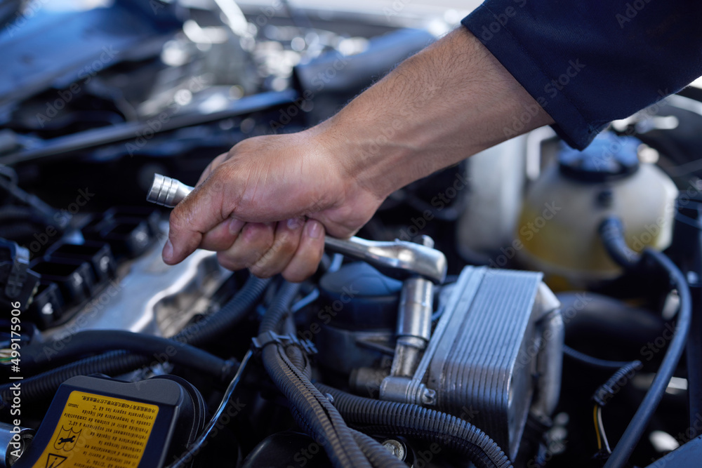 Poster safety first. high angle shot of an unrecognizable male mechanic working on the engine of a car duri