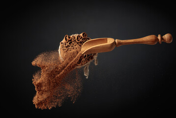 Cinnamon powder is poured out of the wooden spoon.