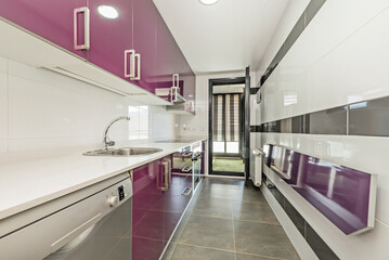 Kitchen with white stone countertops, bright purple wood cabinets and folding table and aluminum radiator and stainless steel appliances