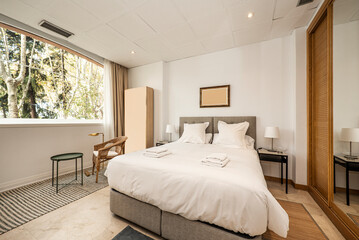 Double bed with folding sofa, wooden sliding door wardrobe and mirror and window overlooking a park