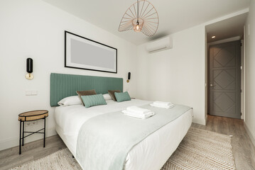 bedroom with double bed with white folded towels, blue fabric upholstered headboard, matching...