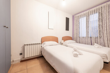 Bedroom with two single beds with light wood headboards, gray wardrobe and window with curtains