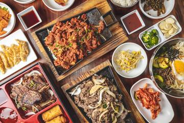 Overhead Korean bulgogi barbecue flat lay view of a dinner feast with multiple bowls and platters...