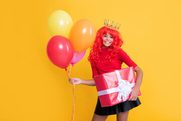 happy child in crown with present box and party balloon on yellow background