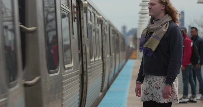 A transwoman waits for a train in a city
