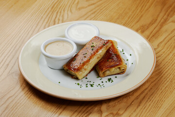 Pancakes with meat, with sauce and sour cream, decorated with herbs