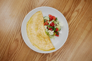 big omelet with vegetable salad
