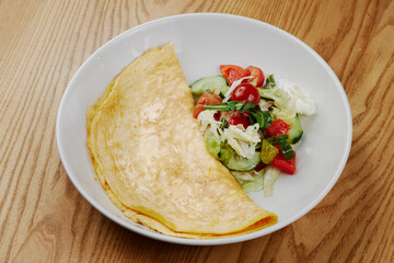 big omelet with vegetable salad